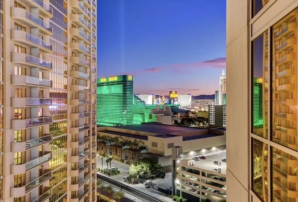 Un hotel de gran altura con varios balcones, vista al casino MGM Grand y un área de estacionamiento al frente.