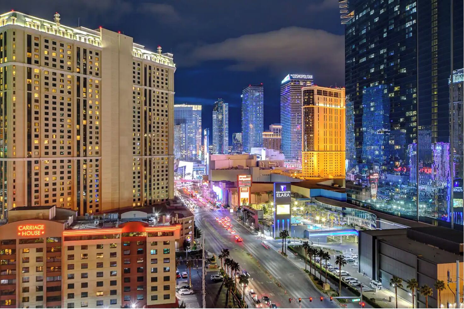 A cityscape with illuminated buildings, including a hotel named 'Carriage House' and 'Elara'.