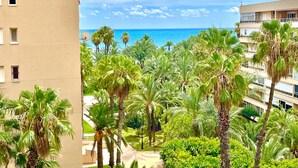 Uitzicht op een hotel met palmbomen en een helderblauwe lucht.