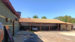 A building with a tiled roof, a covered parking area, and a gravel driveway. - Pousada Paraiso (Wanderley)