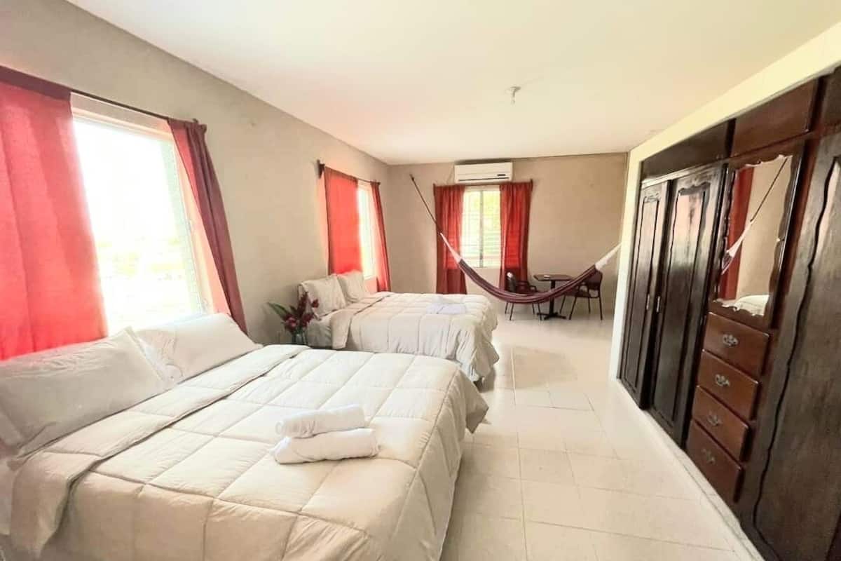 A hotel room with two beds, a desk, a chair, and a wardrobe.