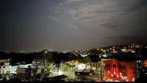 Vista nocturna de un pueblo con edificios y una estructura roja destacada en primer plano.