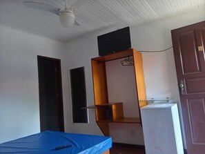 Cozy retreat with a single bed, refrigerator, and shelving unit.