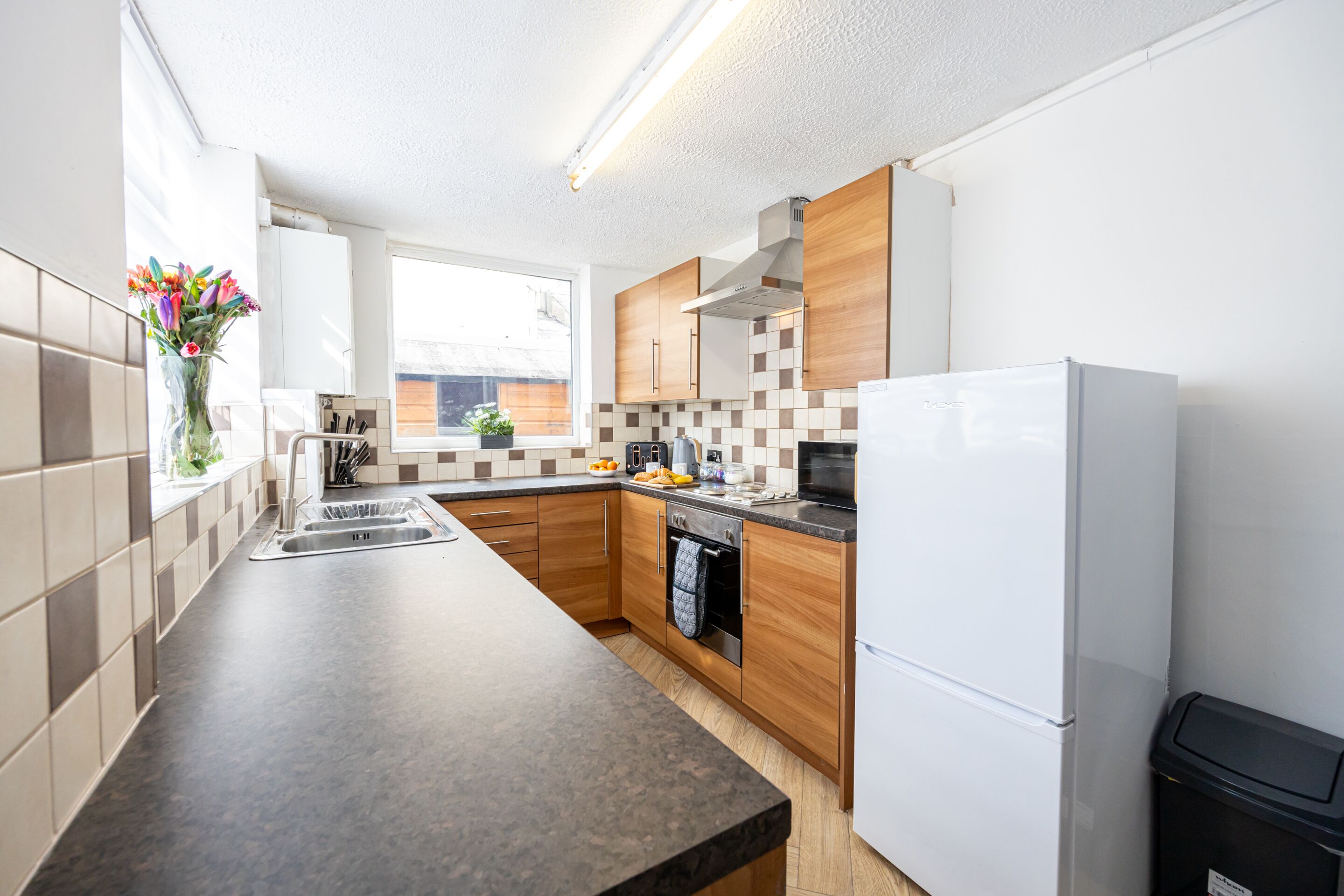 A modern kitchen with a built-in oven, a sink, and a refrigerator.