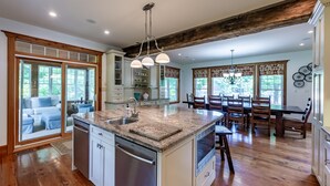 A spacious kitchen with a central island, wooden flooring, and a dining area with a large table and chairs. - 8 bed 5 bath cottage on Lake Muskoka, 9 acres! (Torrance)
