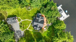 An aerial view of a residential area with two houses, a dock, and a body of water. - 8 bed 5 bath cottage on Lake Muskoka, 9 acres! (Torrance)
