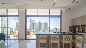 Una cocina moderna con una isla grande, taburetes de bar y vistas a la ciudad a través de ventanales de piso a techo.