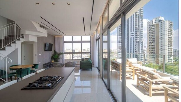 Un apartamento moderno con cocina, comedor y balcón con vistas a la ciudad.
