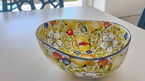 A dining table with a colorful bowl, a chair, a TV, and a view of the sea. - Apartment with sea-view balcony from which to admire magical sunrises. (Castro)