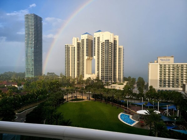 A hotel with a pool, surrounded by palm trees and a view of tall buildings.