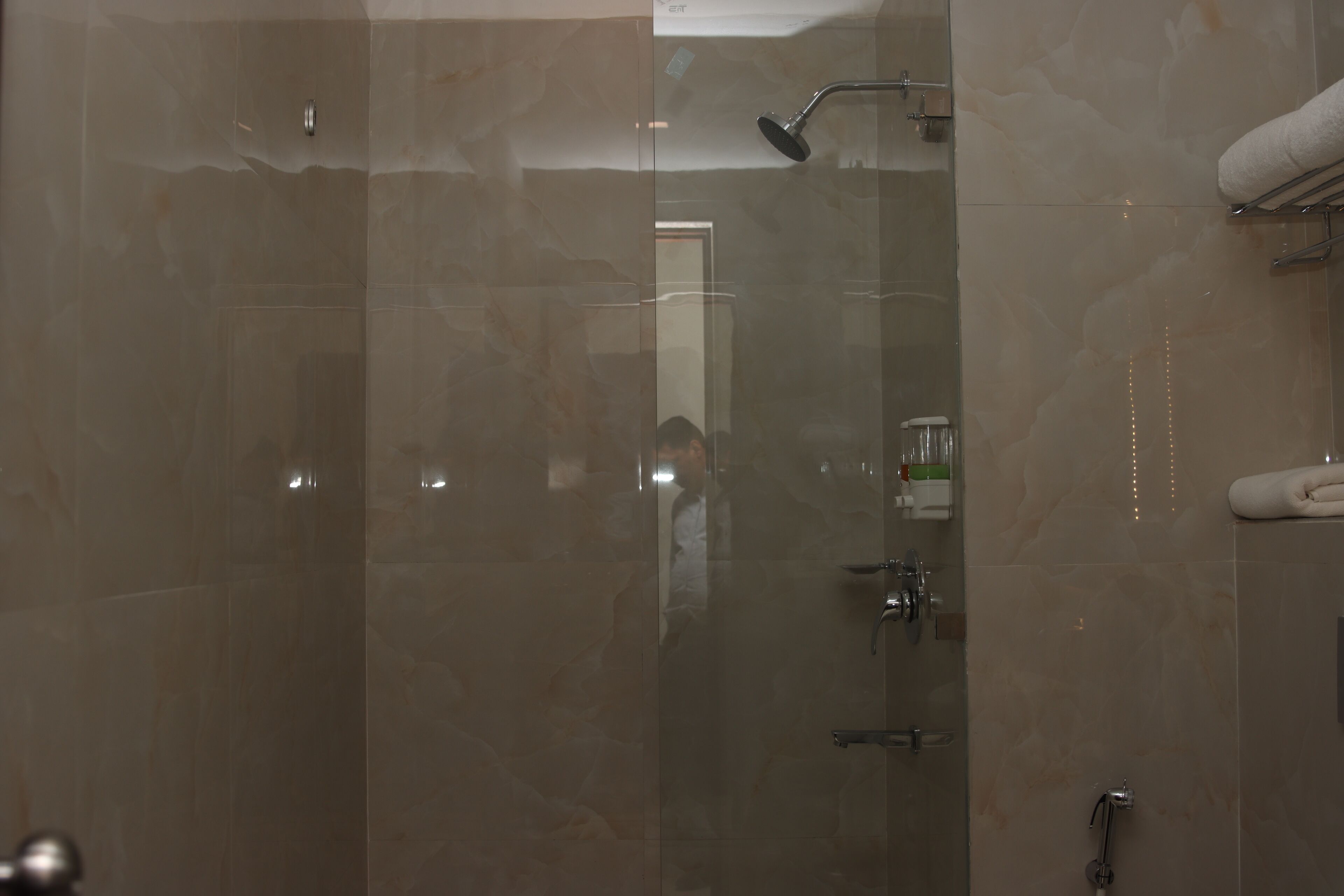 Un baño con cabina de ducha de vidrio, un perchero y una puerta visible.