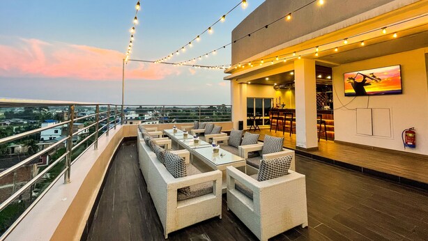 A rooftop bar with outdoor seating, string lights, and a television screen. - Nepalirika Hotel Biratchowk (Sundar Haraicha)