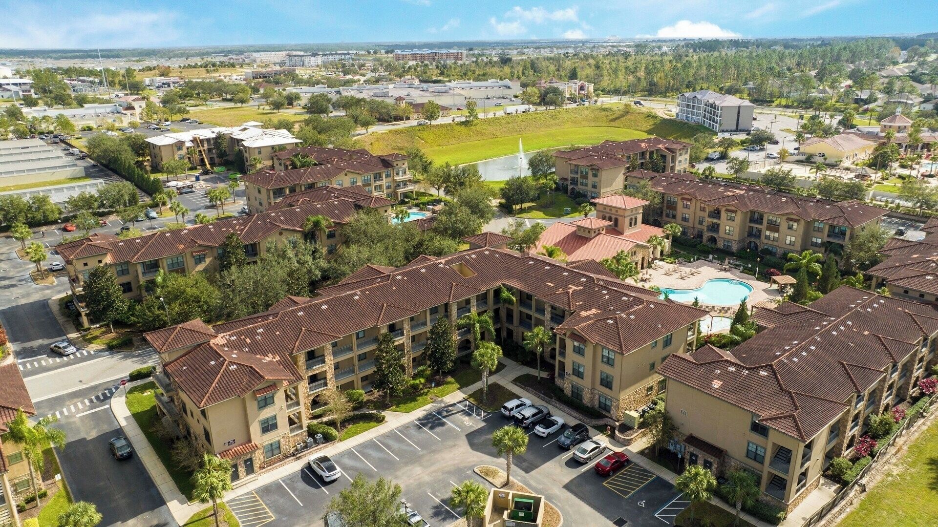 A residential complex with multiple apartment buildings, a swimming pool, and a parking area.