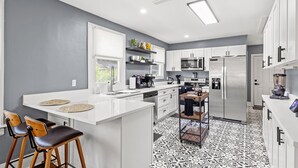 A modern kitchen with white cabinetry, a central island, and a patterned floor. - Fancy Dancy (Jacksonville)