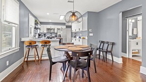 A modern kitchen with white cabinets, a central island, and a dining area with a round table and chairs. - Fancy Dancy (Jacksonville)