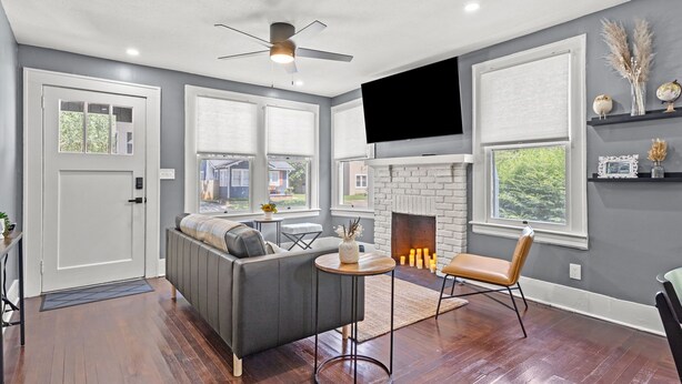 A modern living room with a grey sofa, a fireplace, and a flat-screen TV mounted on the wall. - Fancy Dancy (Jacksonville)