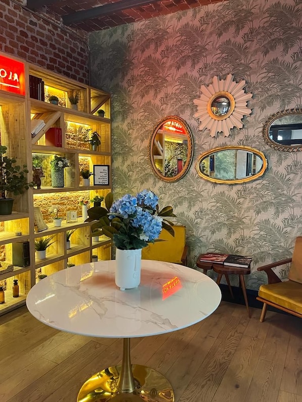 A room with a round table, a bookshelf, and decorative mirrors.