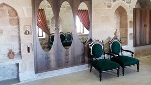 A room with stone walls, a mirrored wardrobe, and two green upholstered chairs. - Kale Divan Konağı (Mardin)