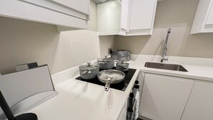 A modern kitchen with white cabinets, a stainless steel sink, and a black countertop. - Charming 1 bedroom flat with FAST Wi-Fi near The Shard and Elephant & Castle (London)