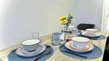 A dining table set with blue and white patterned plates, clear glasses, and a vase with yellow flowers.