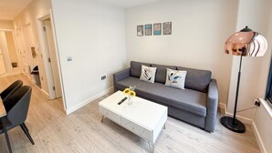 A modern living room with a grey sofa, a white coffee table, and a floor lamp. - Charming 1 bedroom flat with FAST Wi-Fi near The Shard and Elephant & Castle (London)