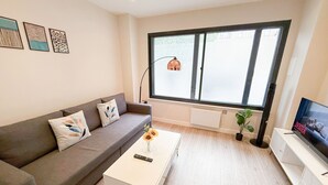 A modern living room with a grey sofa, a white coffee table, and a TV on a stand. - Charming 1 bedroom flat with FAST Wi-Fi near The Shard and Elephant & Castle (London)