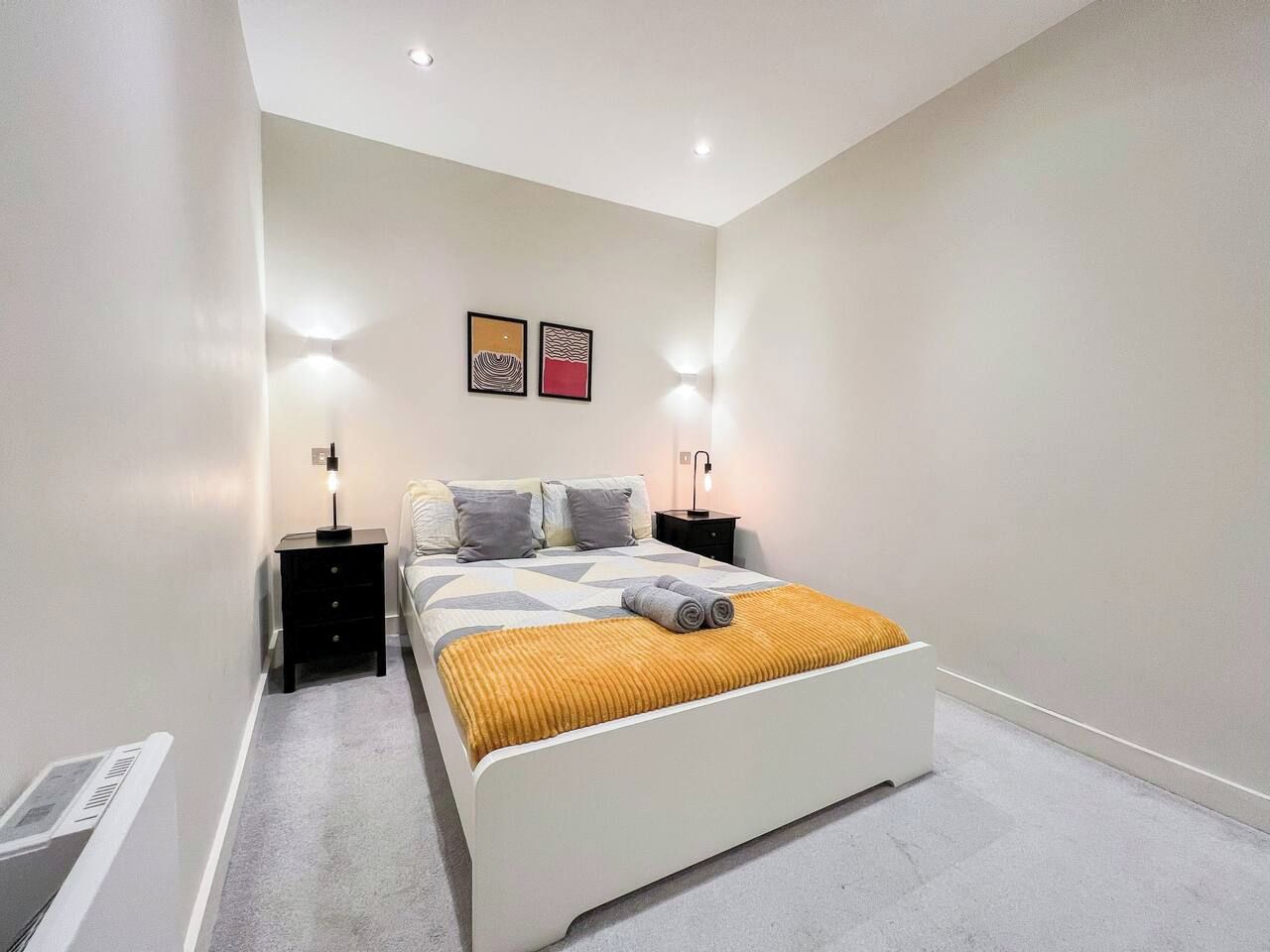 A modern bedroom with a white bed, two bedside tables, and a headboard.