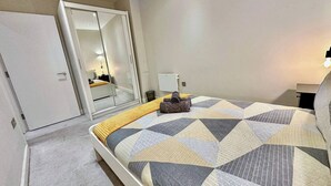 Un dormitorio con cama, armario, espejo y mesita de noche.