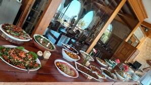 Una mesa de comedor con diversos platos y vistas al interior de un edificio a través de una ventana de vidrio.