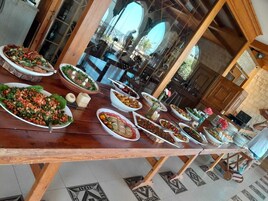 Mesa de jantar com diversos pratos e vista do interior de um edifício através de uma janela de vidro.