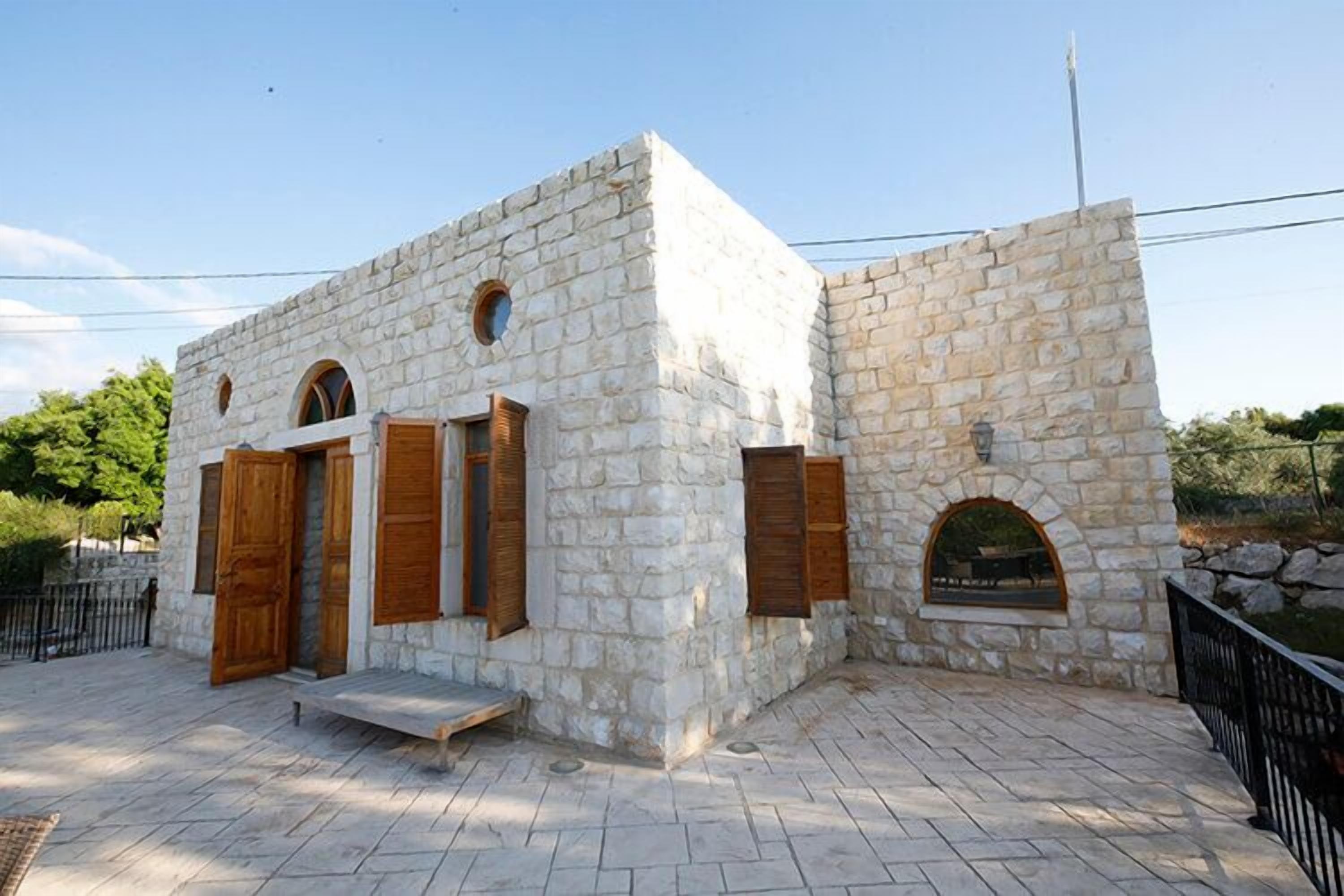 A stone building with wooden shutters and a small porch.