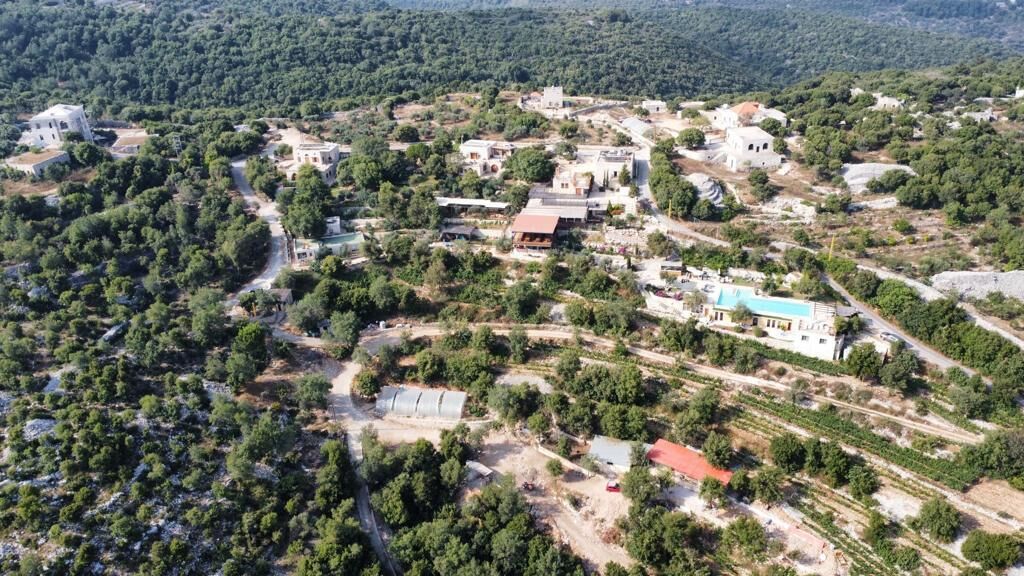 Vista aérea de una zona rural con edificios dispersos, caminos y vegetación.