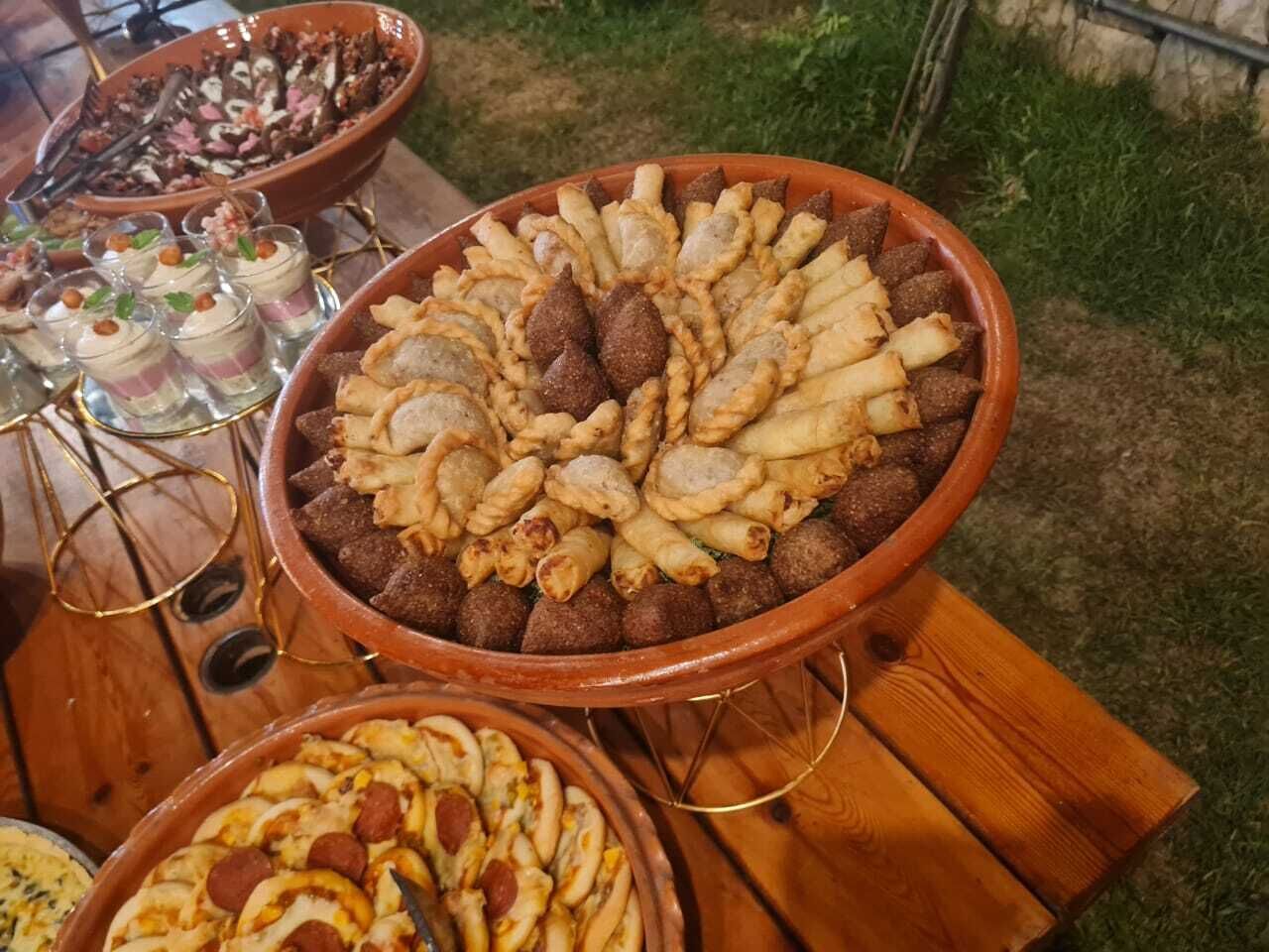 A variety of baked goods displayed on a wooden table outdoors.