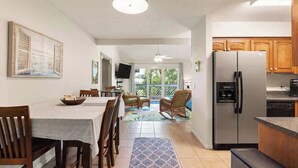 A kitchen with a dining area, a refrigerator, wooden cabinets, and a television. - Perch in Paradise on St Simons Island (St. Simons Island)