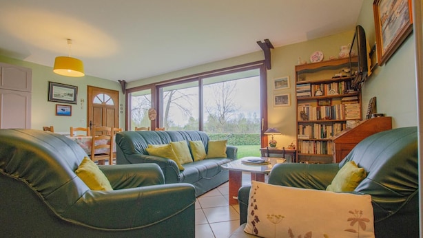 Een gezellige woonkamer met een groene bank, een bijzettafeltje en een boekenplank vol boeken.