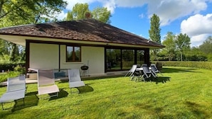 Een modern huis met een overdekte patio, een gazon en buitenmeubels.