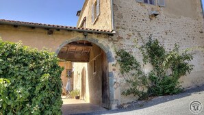 Un bâtiment rustique en pierre, doté d’une entrée en arc de cercle, d’une porte en bois et d’une petite fenêtre avec des volets.