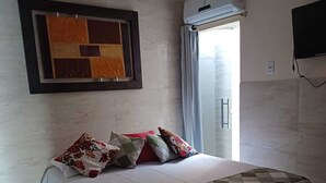 A bedroom with a bed, pillows, a quilt, an air conditioning unit, and a TV on the wall. - Casa Aconchegante em Santa Cruz Cabrália -Ba (Santa Cruz Cabrália)