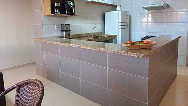 A modern kitchen with a granite countertop, white cabinets, and a built-in stove. - Casa Aconchegante em Santa Cruz Cabrália -Ba (Santa Cruz Cabrália)