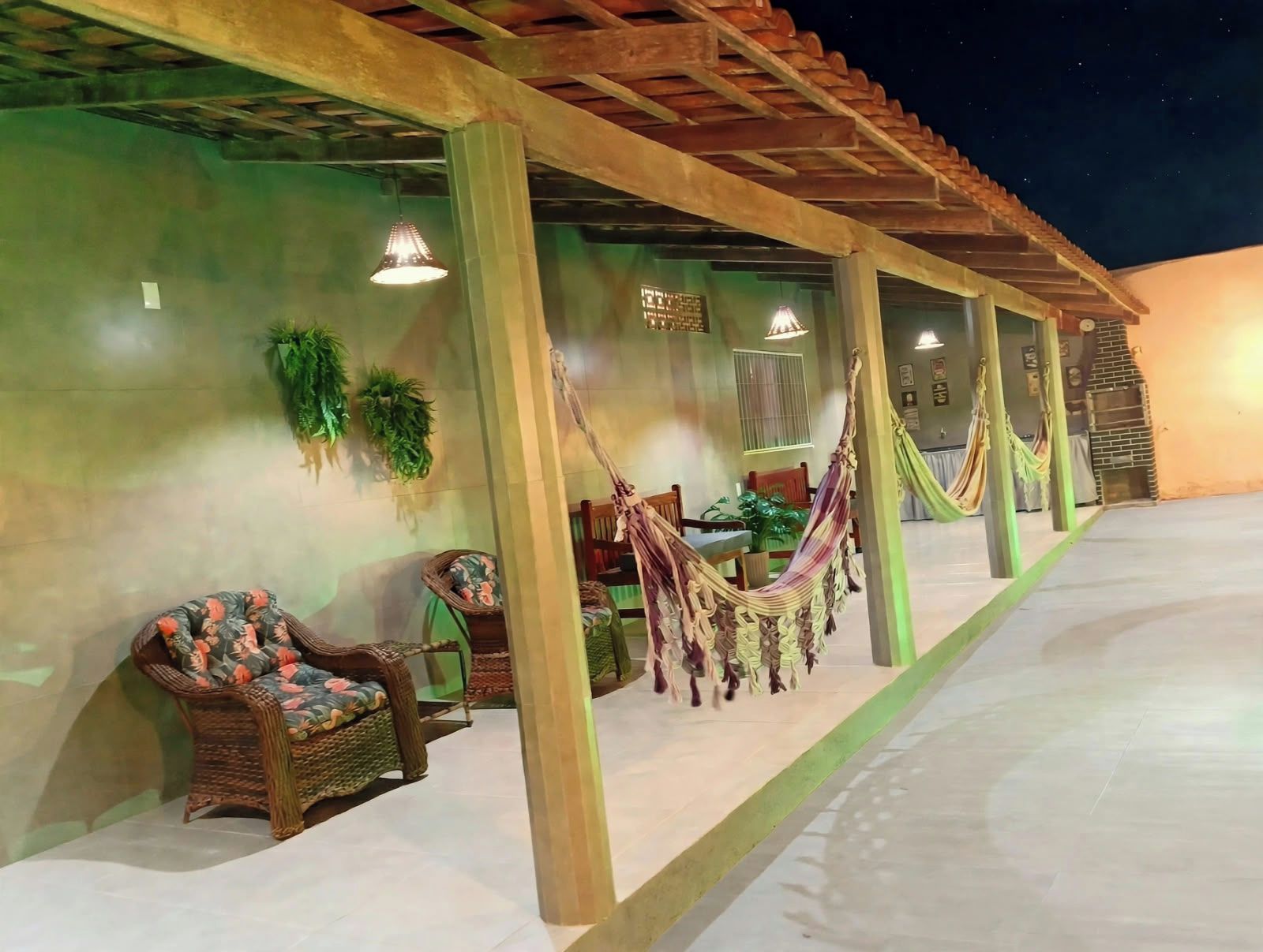 A covered outdoor seating area with hammocks, wicker furniture, and a pergola structure.