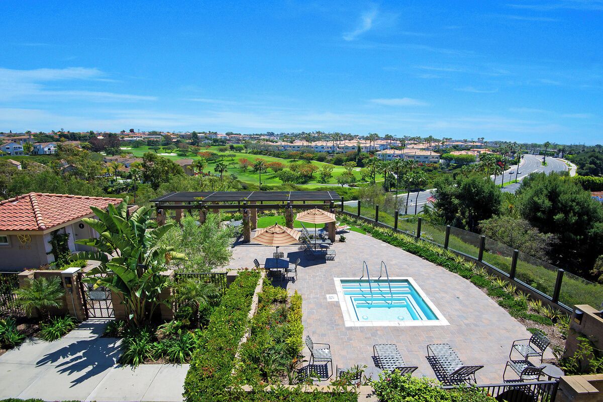A rooftop pool area with a view of a golf course and residential buildings.