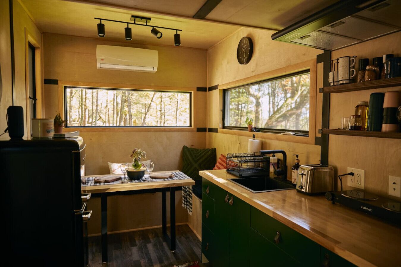 A compact kitchen with a wooden countertop, a sink, a toaster, and a clock on the wall.