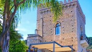 A stone tower with a balcony and a covered outdoor seating area.