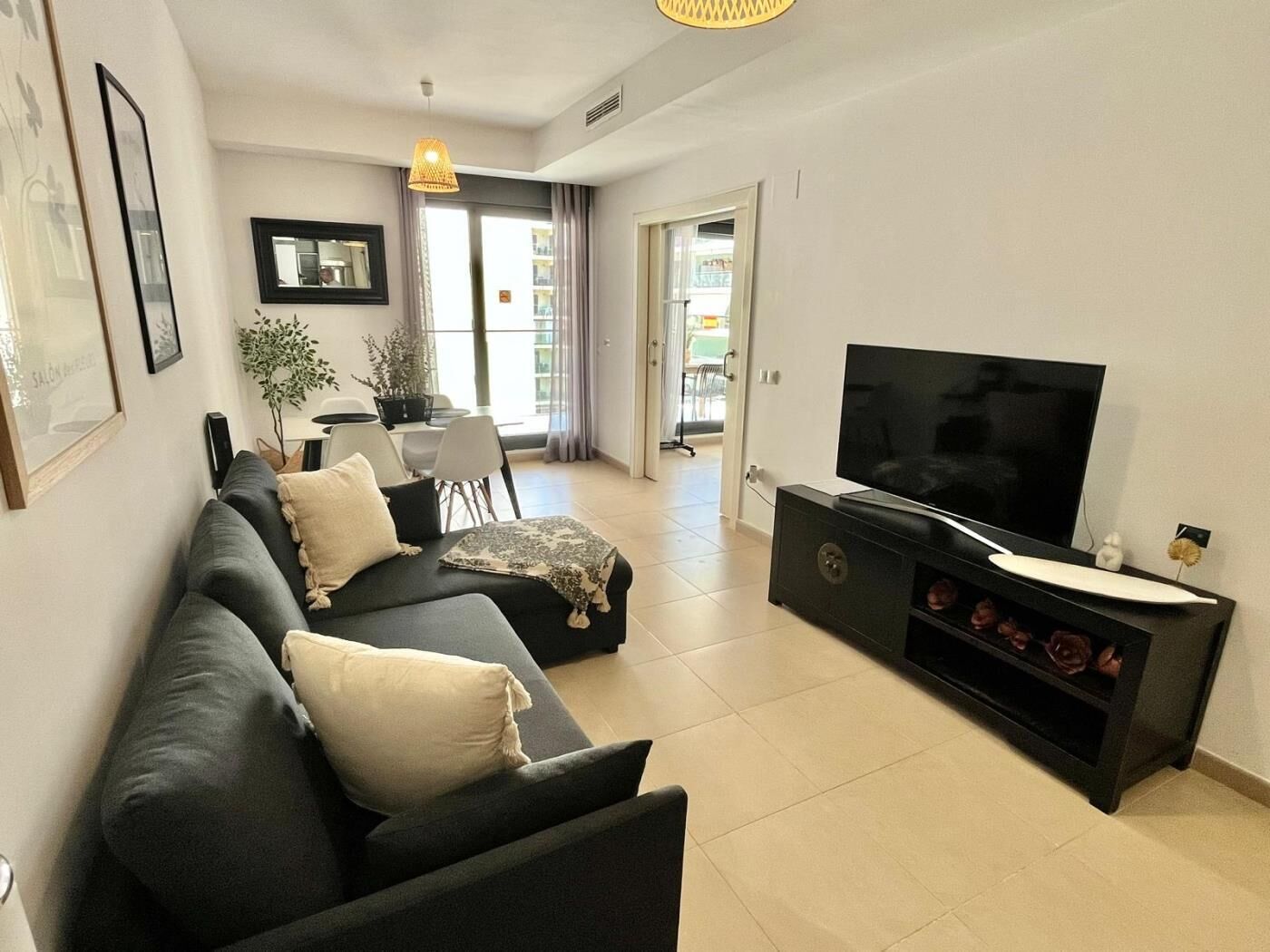 En moderne stue med en sofa, et fladskærms-TV og et spiseområde med et bord og stole.