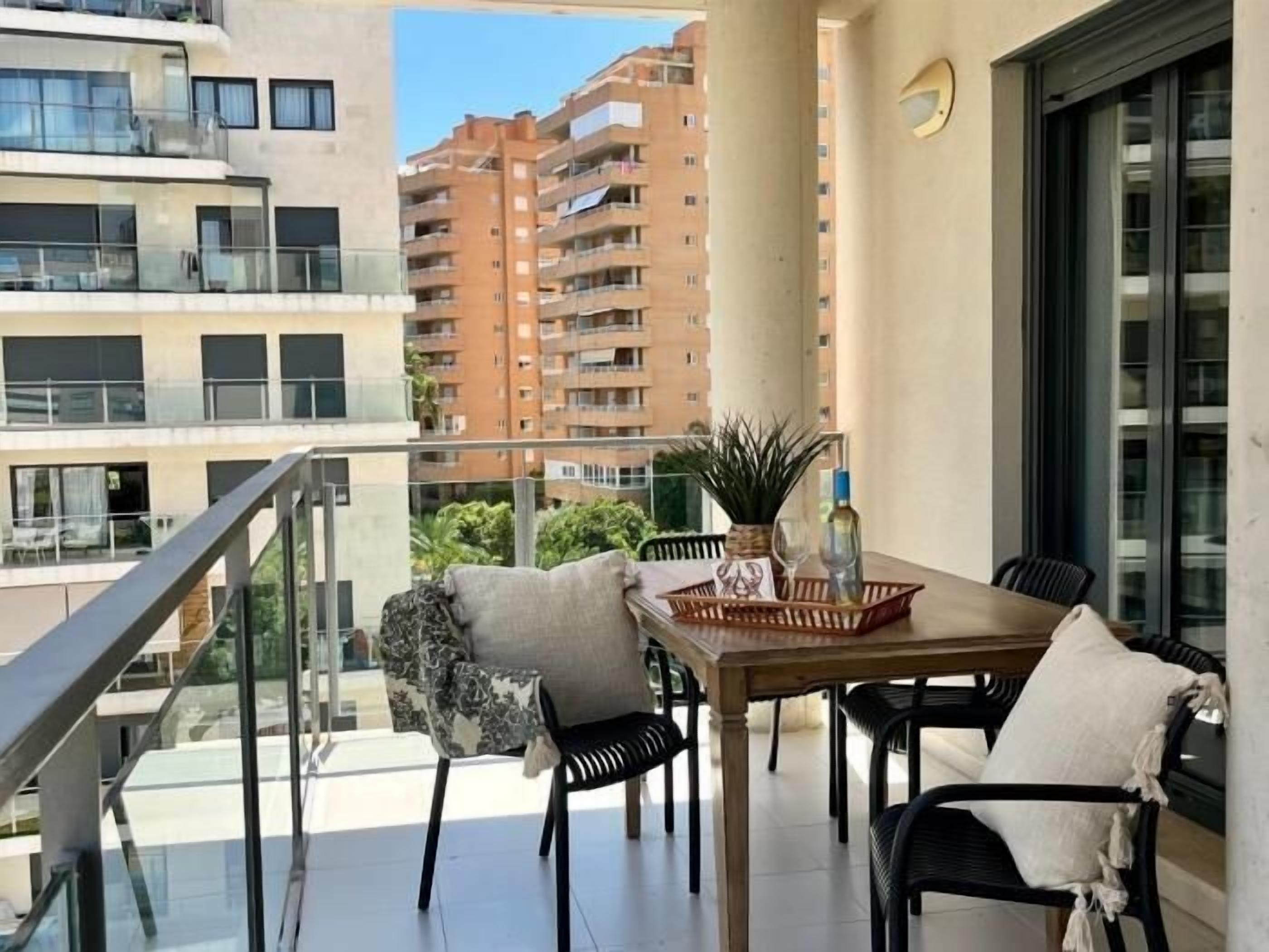 A balcony with a table, chairs, and a potted plant.