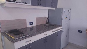 Cozinha com armários cinzas, bancada de granito, pia e geladeira.