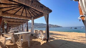 A beachside restaurant with outdoor seating and a view of the sea.