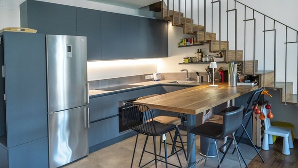 Een moderne keuken met een roestvrijstalen koelkast, een houten eiland met barstoelen en een inbouwoven.