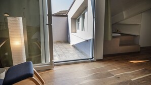 Een modern interieur met een houten vloer, een glazen deur naar een balkon en een stoel.