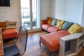 Un salon moderne avec un canapé, un fauteuil et une console blanche.